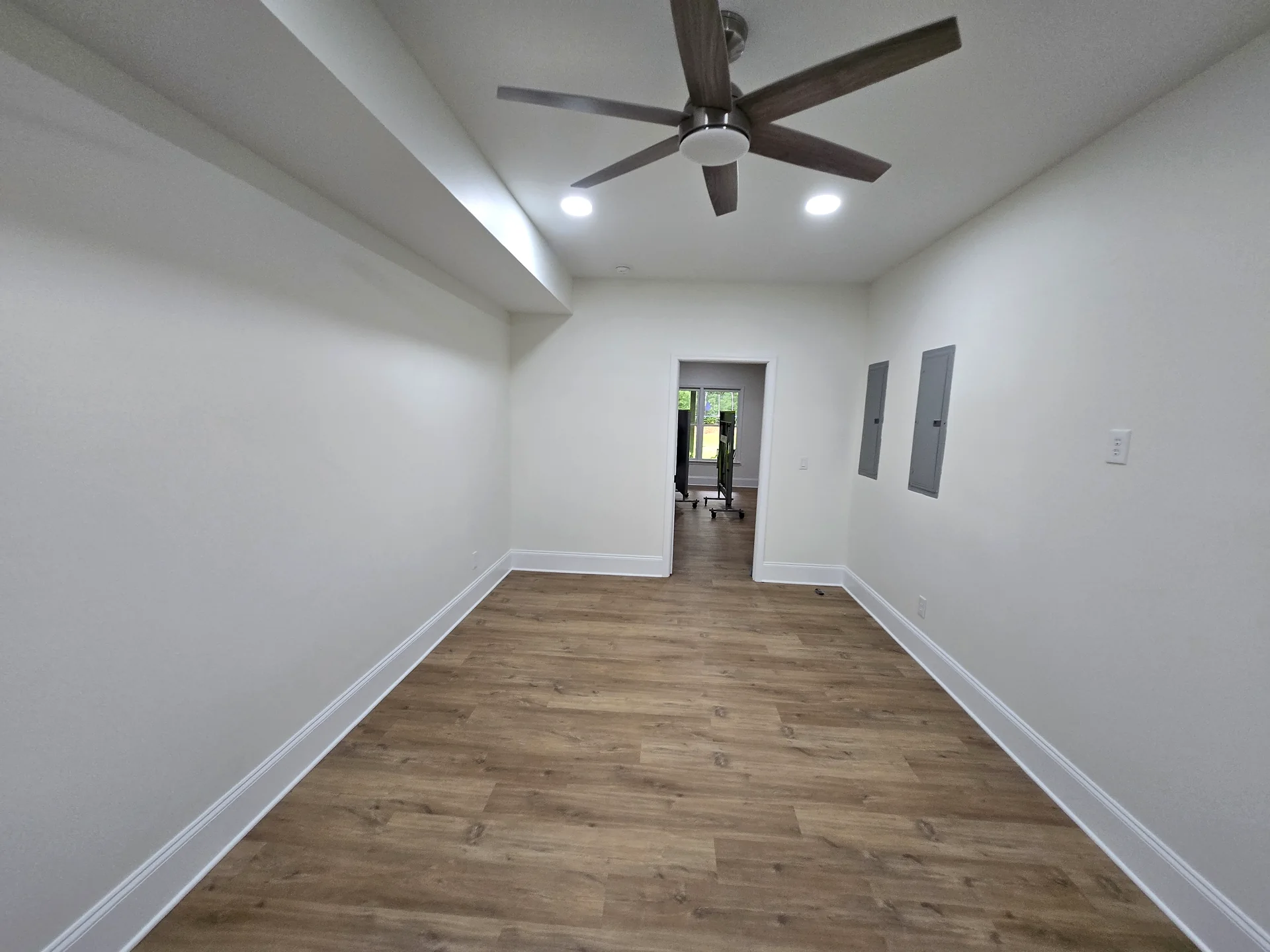 Finished basement room with wood-look flooring, ceiling fan, and recessed lights