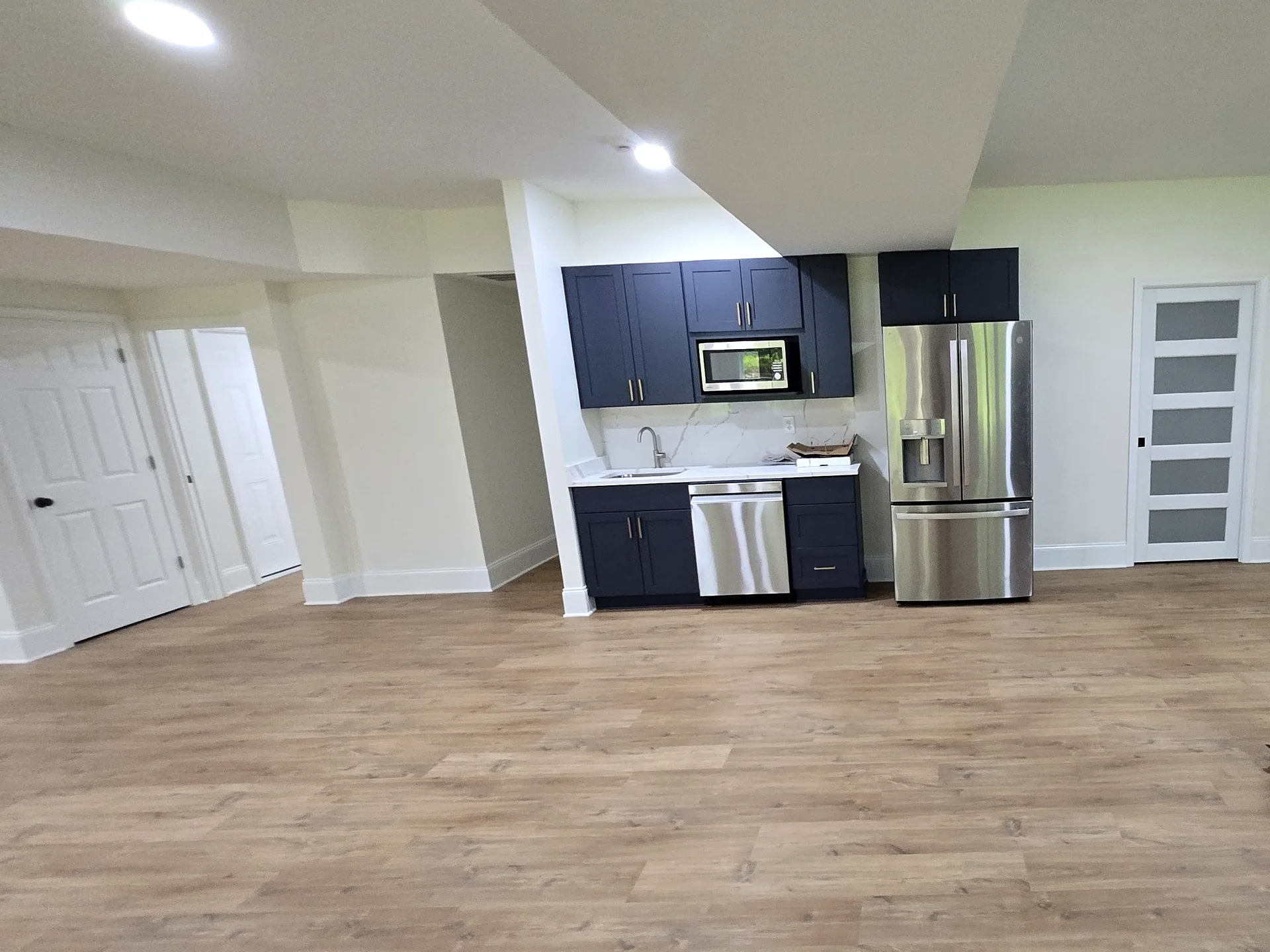 Compact basement kitchenette with dark cabinetry and stainless steel appliances