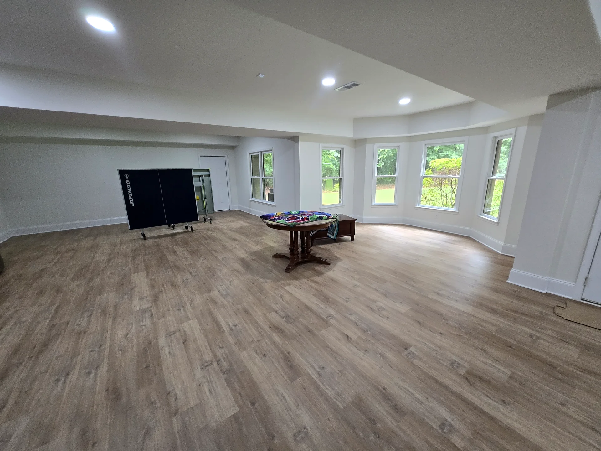Bright finished recreation room with large windows and new wood-look flooring