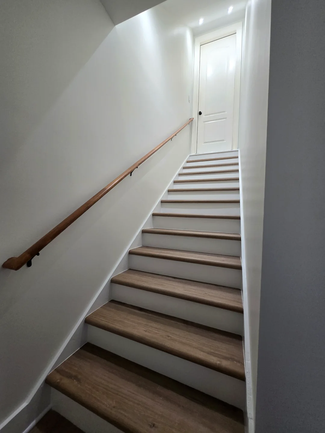 Finished staircase with wood treads and a matching handrail